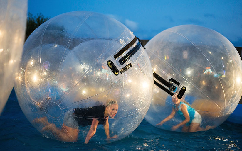 Photo of two girls in wet zorbs on water