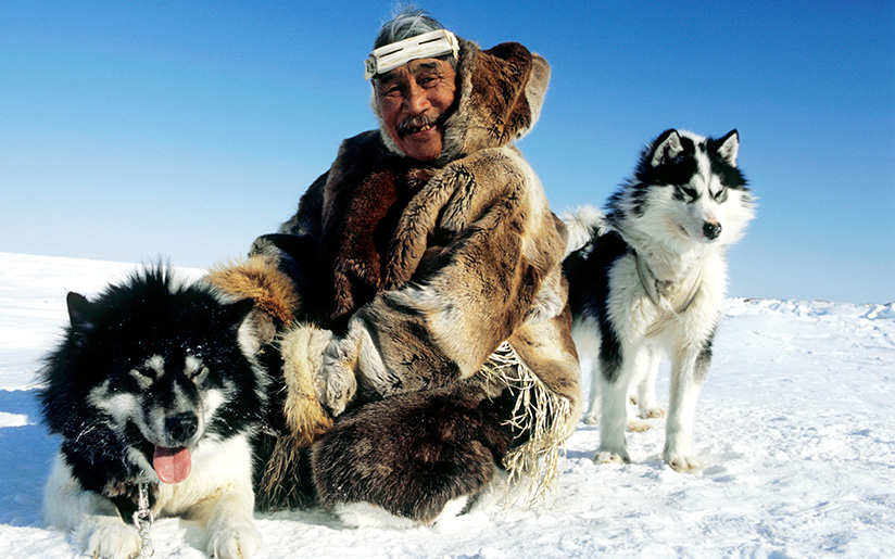 Photo of an Inuit man and his two dogs